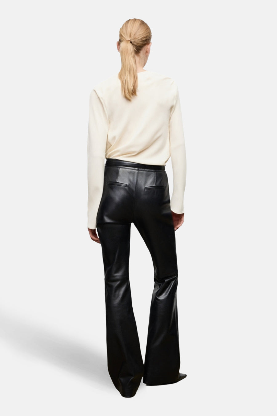 Chemisier écru à manches longues van MANGO, porté avec un pantalon évasé en similicuir noir.
