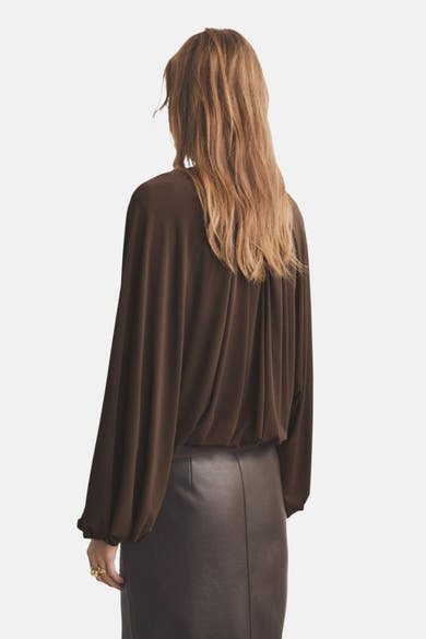 Blouse marron à manches longues de MANGO avec un design ample et une jupe en cuir assortie.