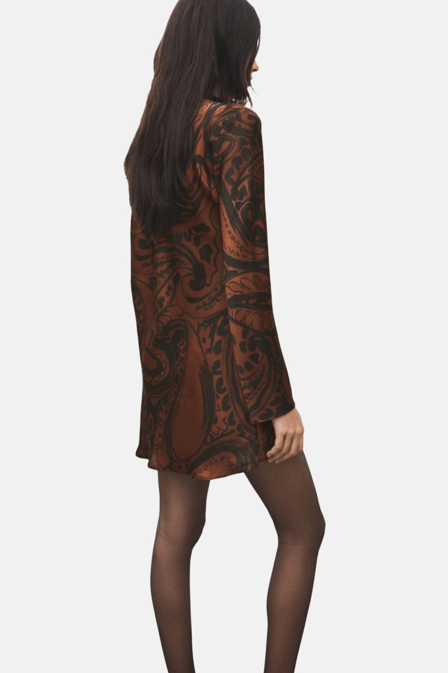 Robe courte imprimée multicolore de MANGO, avec motif cachemire, manches longues et collants noirs.
