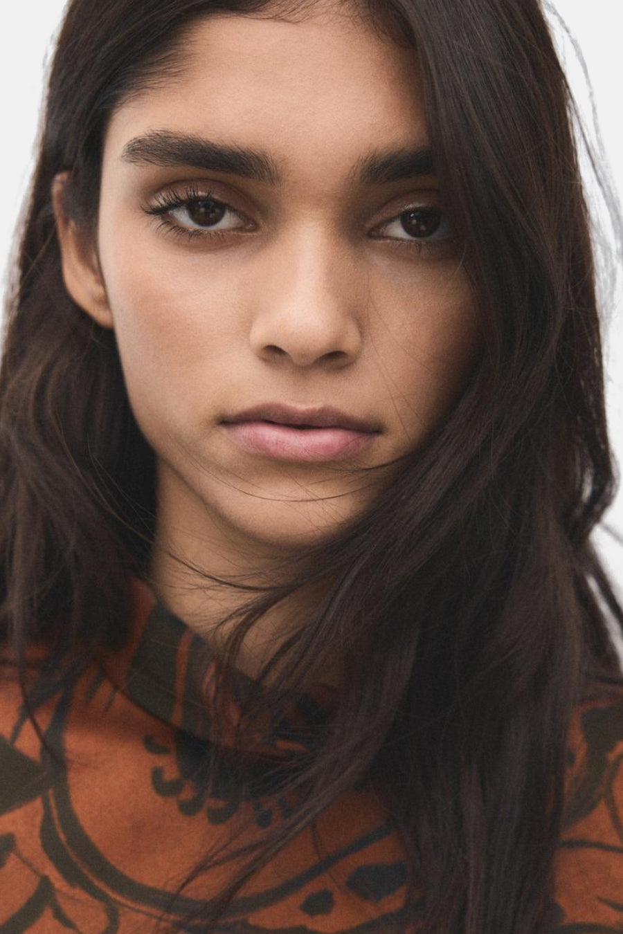 Multikleurige jurk van MANGO, met een abstracte print in aardse en warme tinten, gedragen door een model.