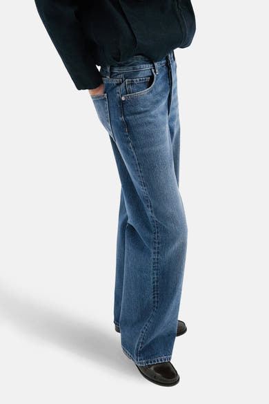 Jean droit en denim bleu moyen de MANGO, porté avec un haut bleu marine et des chaussures noires, vue de côté.
