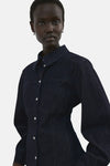 Donkerblauwe spijkerblouse met lange mouwen van MANGO, van achteren gezien, gedragen met een bijpassende broek.