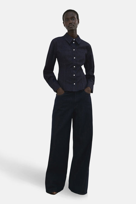 Chemise à manches longues en denim bleu foncé de MANGO, avec une coupe ajustée et des boutons blancs.