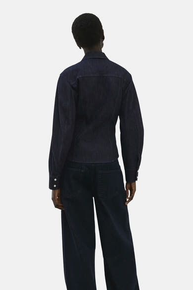 Chemise à manches longues en denim bleu foncé de MANGO, vue de dos, portée avec un pantalon assorti.