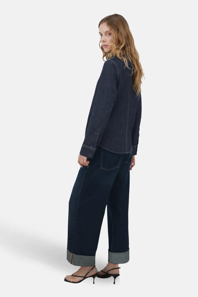 Chemisier denim bleu marine de MANGO, porté avec un jean ample et des sandales à talons.