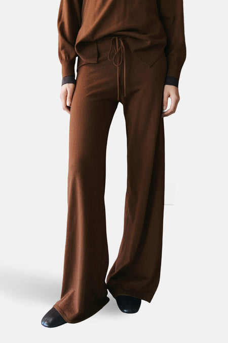 Pantalon brun de MANGO, coupe ample, avec cordon de serrage et chaussures noires.
