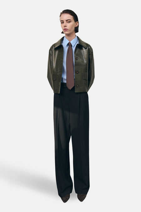 Veste courte kaki de Mango, avec texture crocodile, portée sur une chemise rayée et une cravate marron.