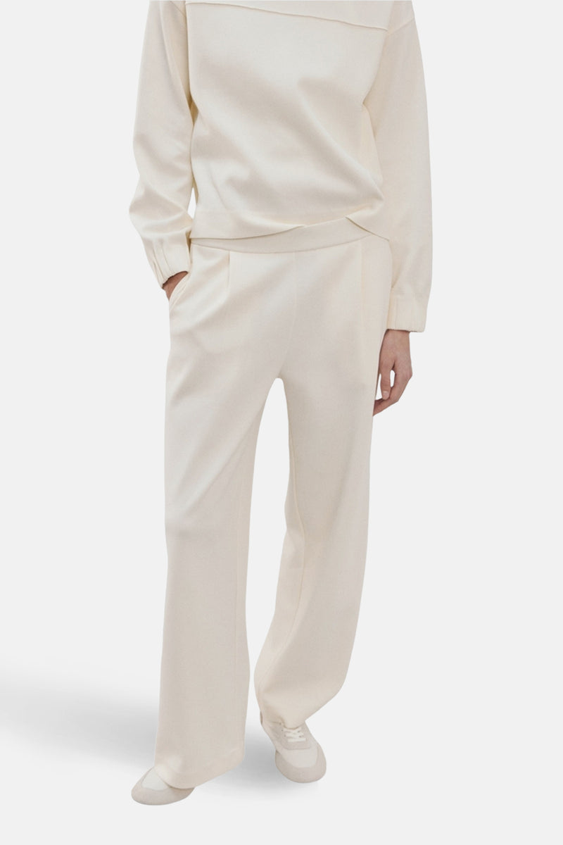 Jogging beige de MANGO, avec une coupe ample et des poches latérales, porté avec un pull assorti et des chaussures de sport.
