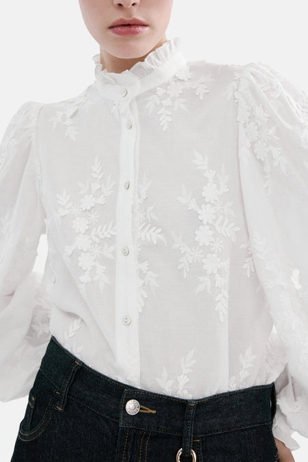 Blouse blanche à manches longues de MANGO, avec broderies florales et col montant volanté.