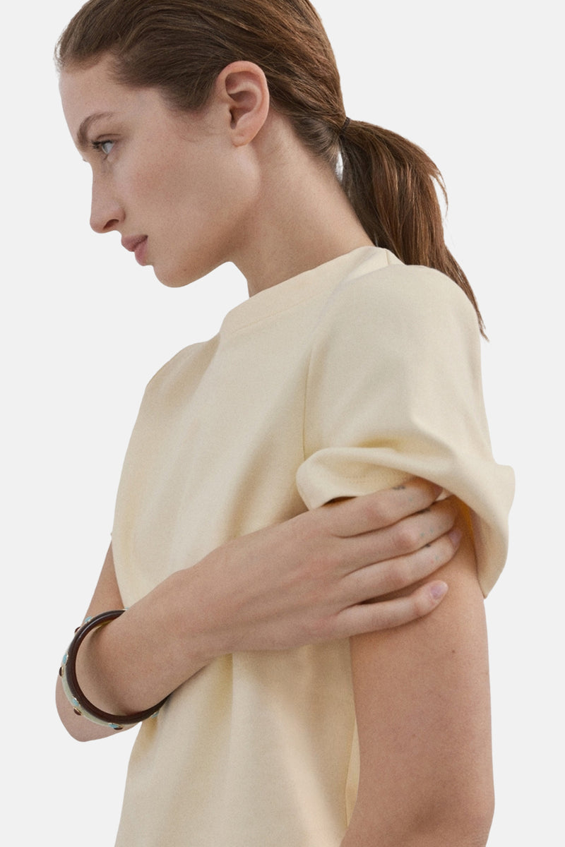 T-shirt jaune à manches courtes de MANGO, porté par un modèle avec un bracelet.
