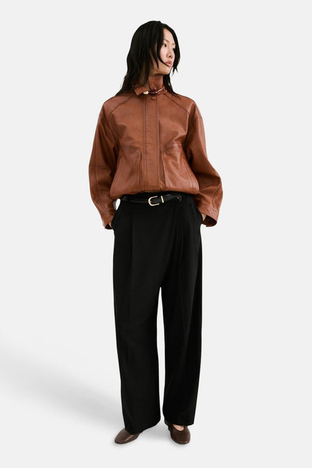 Pantalon noir ample de MANGO, avec ceinture noire et chaussures marron.