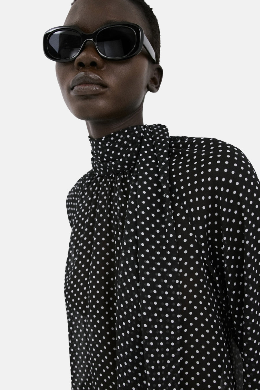 Blouse noire à pois, de MANGO, avec col montant et manches longues bouffantes.