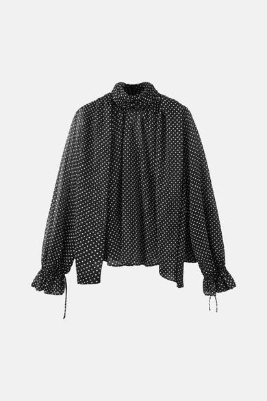 Blouse noire à pois blancs de MANGO, manches longues bouffantes avec volants et liens à nouer.