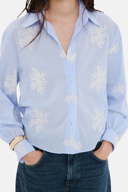 Blauwe blouse met lange mouwen van MANGO, met witte bloemenborduursels over het geheel.