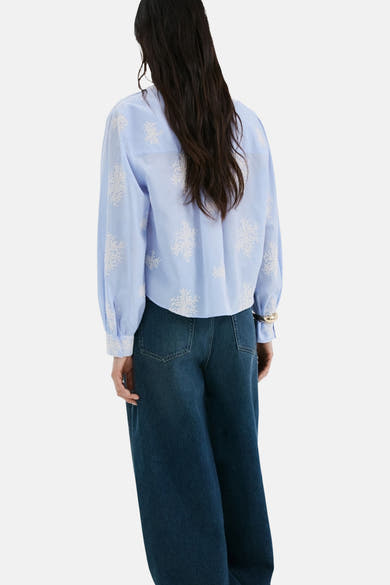 Chemise bleue à manches longues de MANGO, avec broderie florale blanche sur l'ensemble.