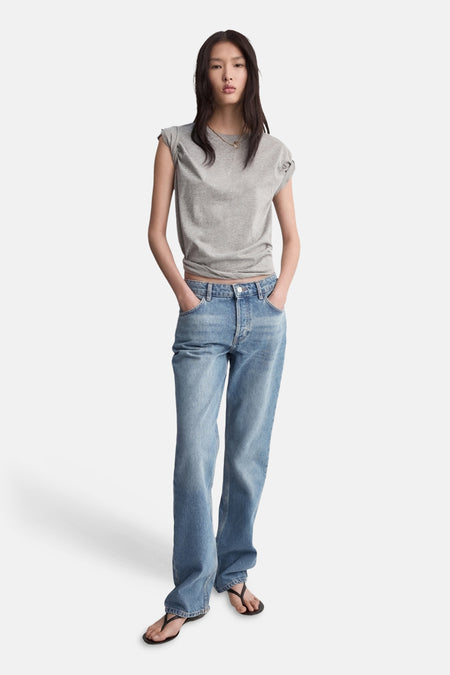 Jean bootcut bleu moyen de MANGO, porté avec un t-shirt gris et des sandales noires.