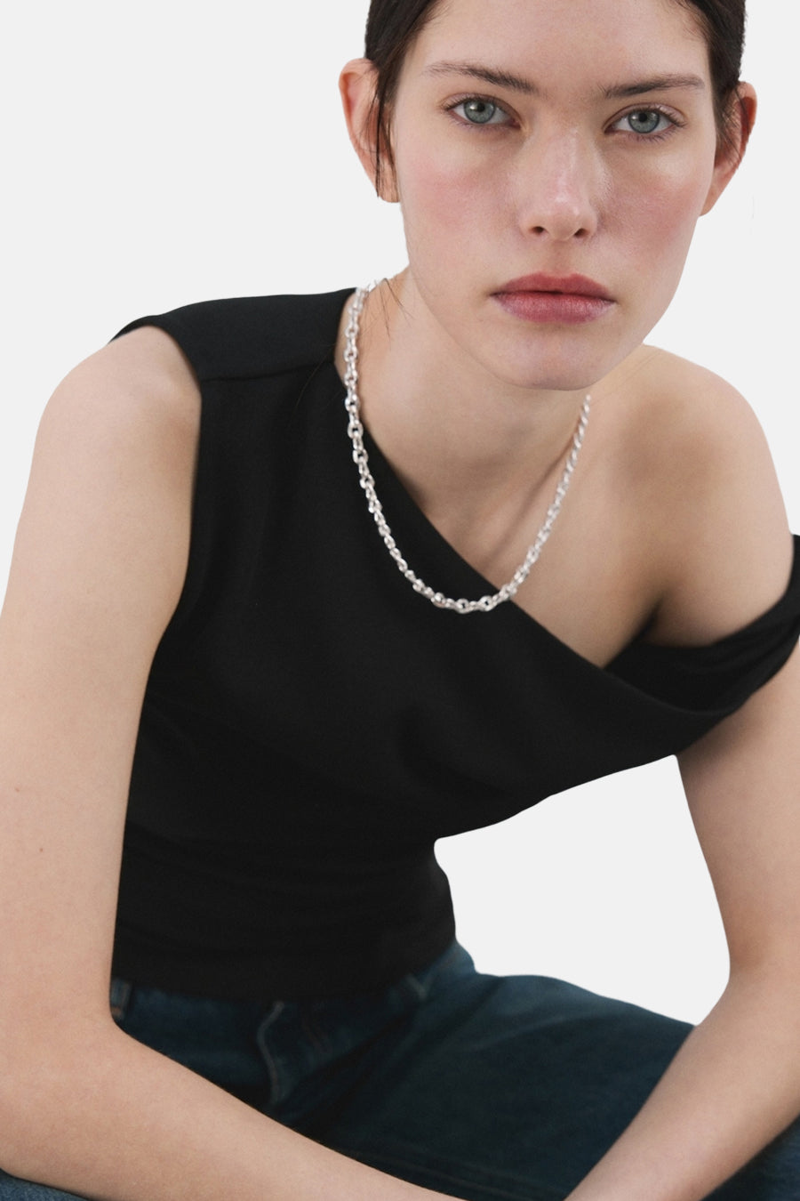 Top sans manches noir de MANGO porté avec un collier argenté et un jean.