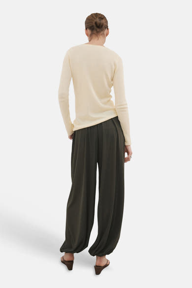 Pull jaune en maille gaufrée de MANGO, col rond, vue de dos, porté avec un pantalon large et des sandales.