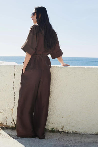 Blouse brune de MANGO à manches courtes retroussées et taille élastiquée, portée avec un pantalon assorti.