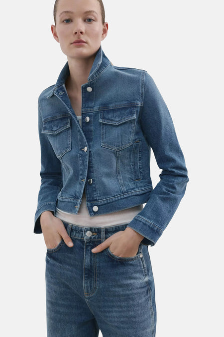 Veste en jean bleu denim de MANGO avec col classique, boutons argentés et poches poitrine, portée avec un jean assorti.