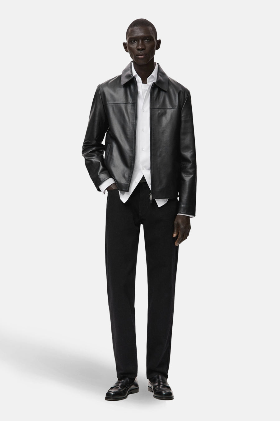 Kort zwart leren jasje, van MANGO, gedragen over een wit overhemd en een zwarte broek, met bijpassende leren schoenen.