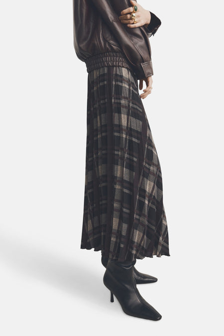 Jupe longue multicolore de MANGO, à carreaux, portée avec un blouson en cuir et des bottines noires.