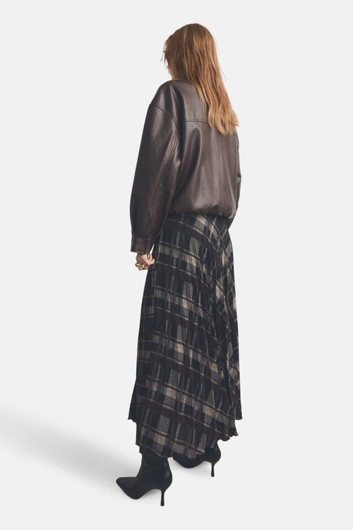 Jupe longue multicolore de MANGO, à carreaux, portée avec une veste en cuir marron et des bottines noires à talons aiguilles.
