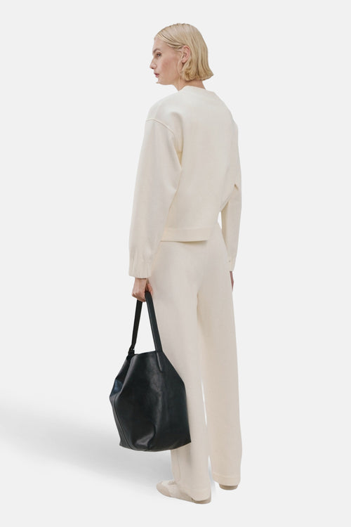 Sweat col rond beige de MANGO, porté avec un pantalon crème et un sac à main noir.