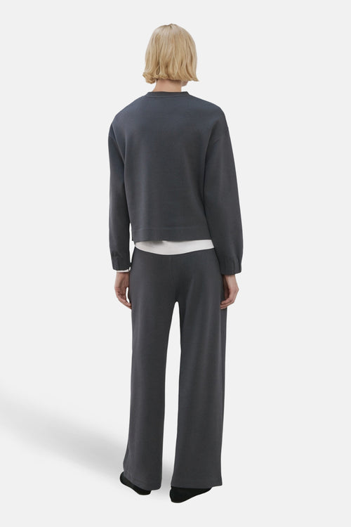 Sweat col rond bleu de MANGO, porté avec un pantalon gris assorti, vue de dos.