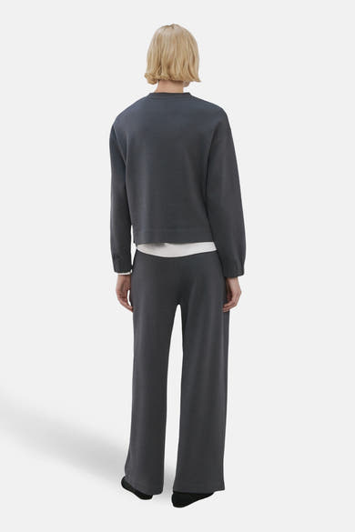 Blauwe rondehals sweatshirt van MANGO, gedragen met een bijpassende grijze broek, achterzicht.
