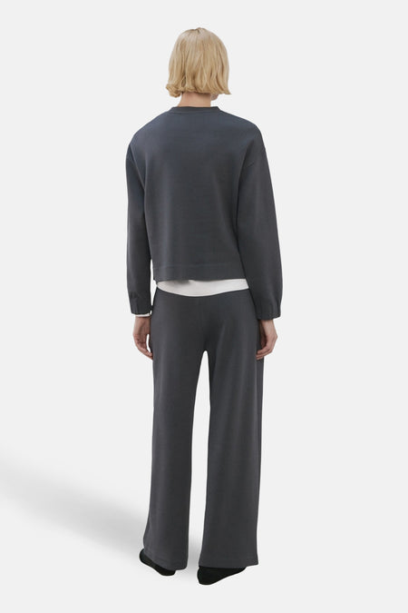 Blauwe rondehals sweatshirt van MANGO, gedragen met een bijpassende grijze broek, achterzicht.