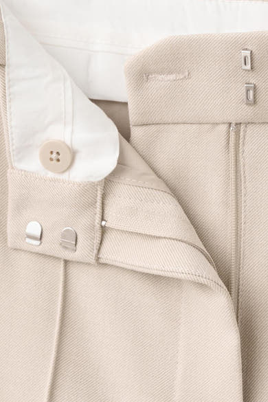 Pantalon beige de MANGO, avec une fermeture à bouton et des agrafes apparentes.