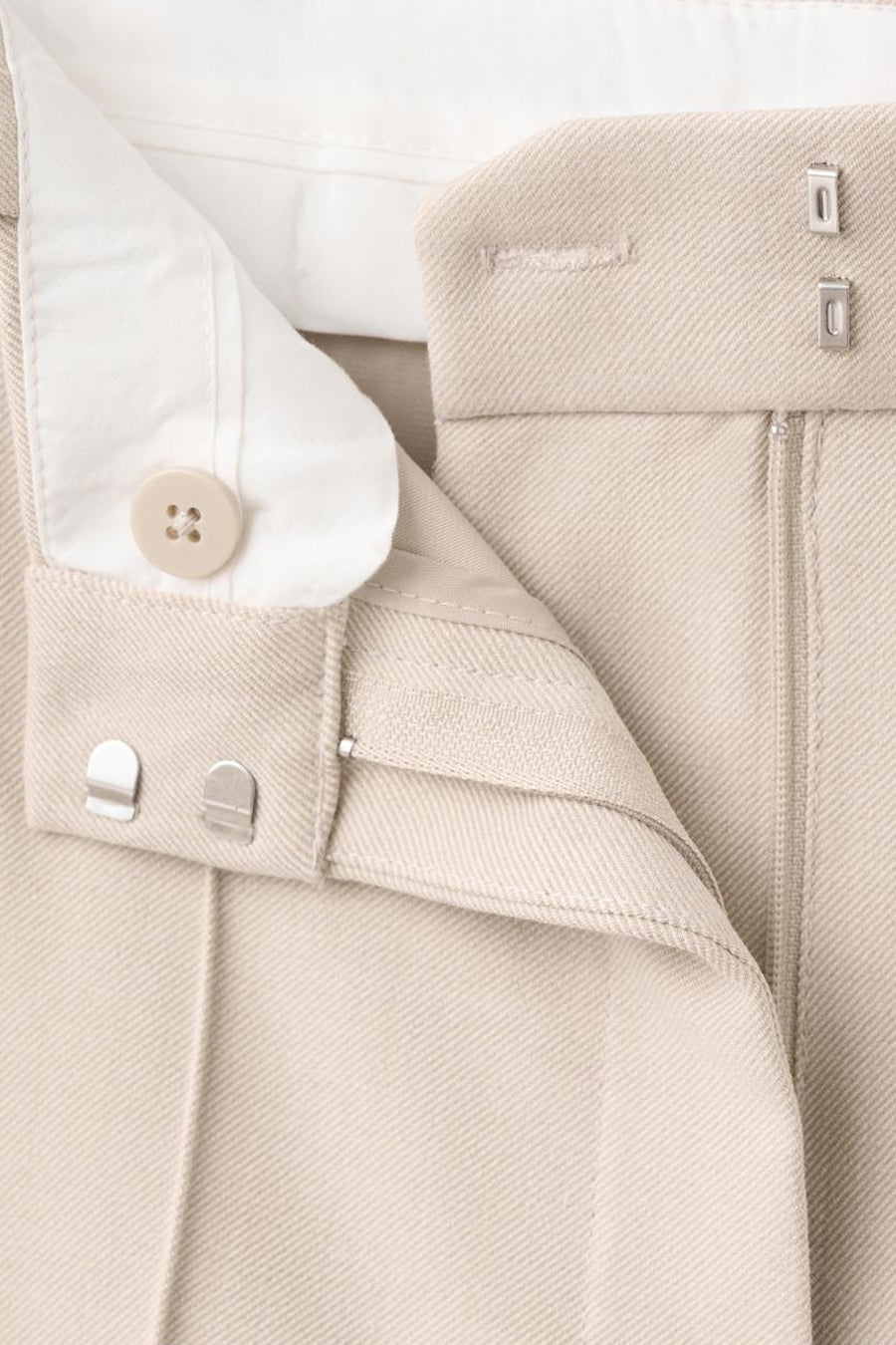 Pantalon beige de MANGO, avec une fermeture à bouton et des agrafes apparentes.