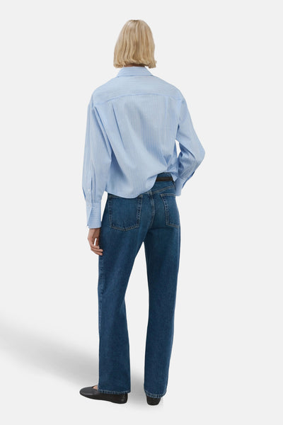 Chemise à manches longues bleue à rayures fines de MANGO, vue de dos, portée avec un jean brut et des chaussures plates noires.