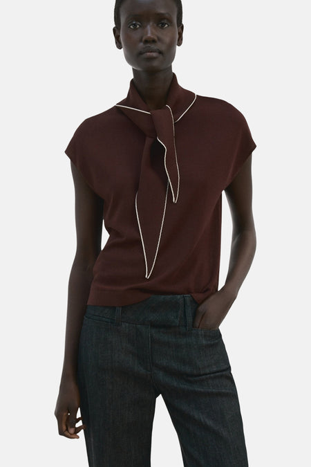Blouse sans manches brune de MANGO, ornée d'un foulard à bordure blanche et portée avec un pantalon sombre.
