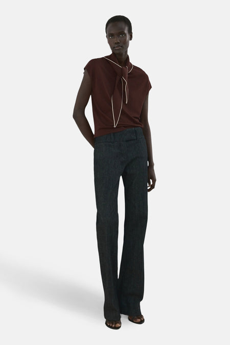 Blouse sans manches brun de MANGO, avec un col à nouer bordé de blanc, portée avec un pantalon taille haute foncé.