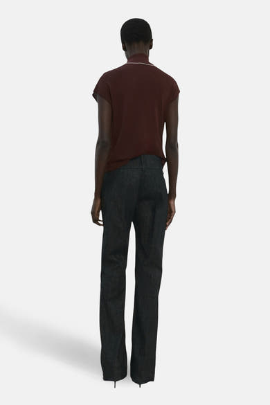 Blouse sans manches brune par MANGO, col montant blanc, portée avec un pantalon de tailleur.
