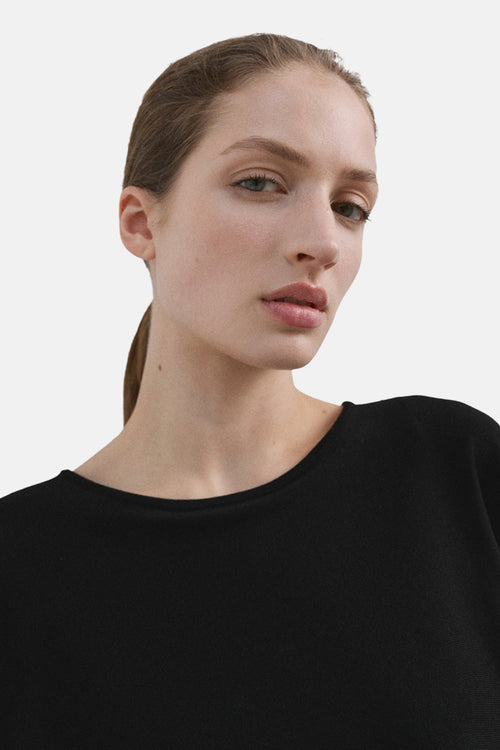 Pull à col rond noir de MANGO, porté par une femme avec un maquillage naturel.