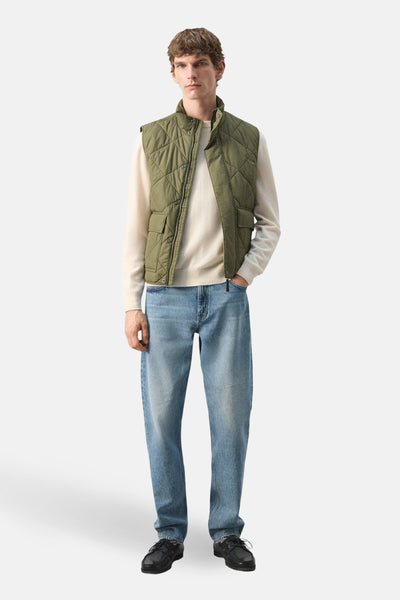 Bodywarmer kaki de MANGO, porté sur un pull couleur crème et un jean bleu clair.