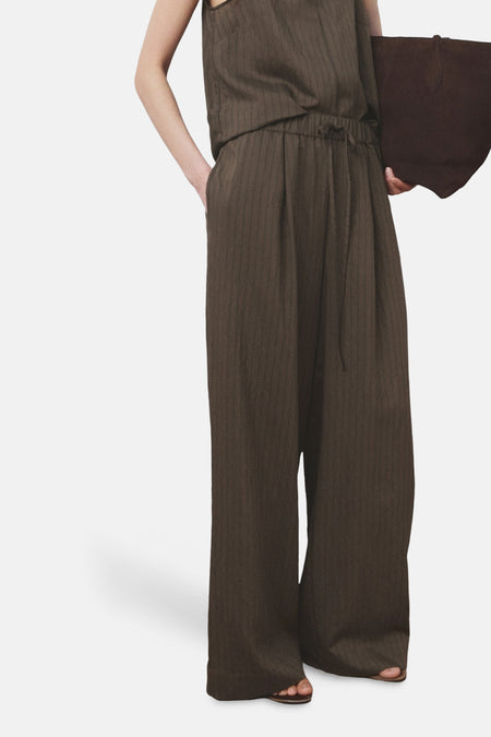 Pantalon ample marron de MANGO, rayures fines verticales, cordon de serrage à la taille et ourlet tombant sur les sandales.