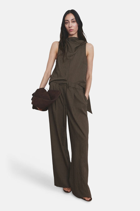 Pantalon brun de MANGO avec une texture rayée portée avec un haut coordonné et un chapeau marron.