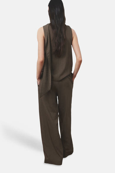 Pantalon brun de MANGO, coupe ample avec poches et texture subtilement rayée, porté avec un haut assorti.