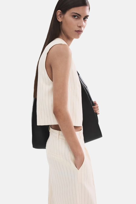 Blouse écru sans manches de MANGO, rayures fines verticales, portée avec un pantalon coordonné, vue de côté.
