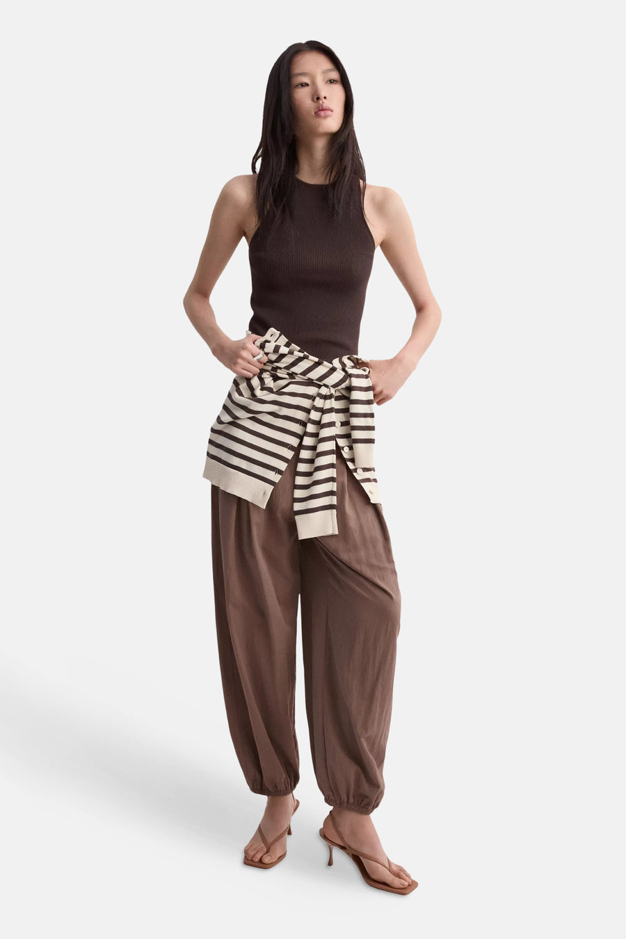 Bruin geribd mouwloos topje van MANGO, gedragen door een model met een wijde bruine broek en een gestreepte trui die is vastgebonden.