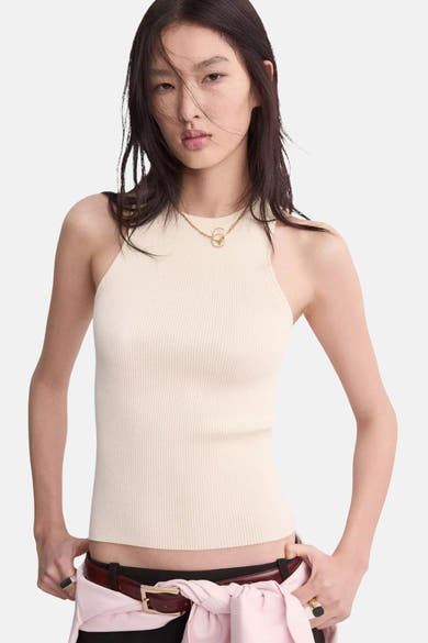 Beige geribd hemdje van MANGO, gedragen met een donkere riem en een roze overhemd geknoopt in de taille.