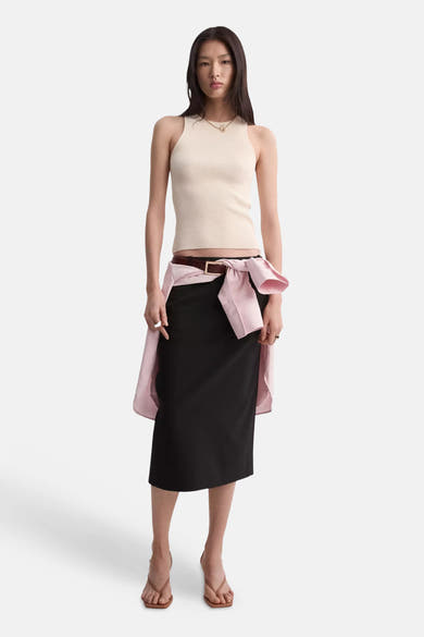 Beige geribd mouwloos topje van MANGO, gedragen met een zwarte rok en een roze geknoopte blouse.