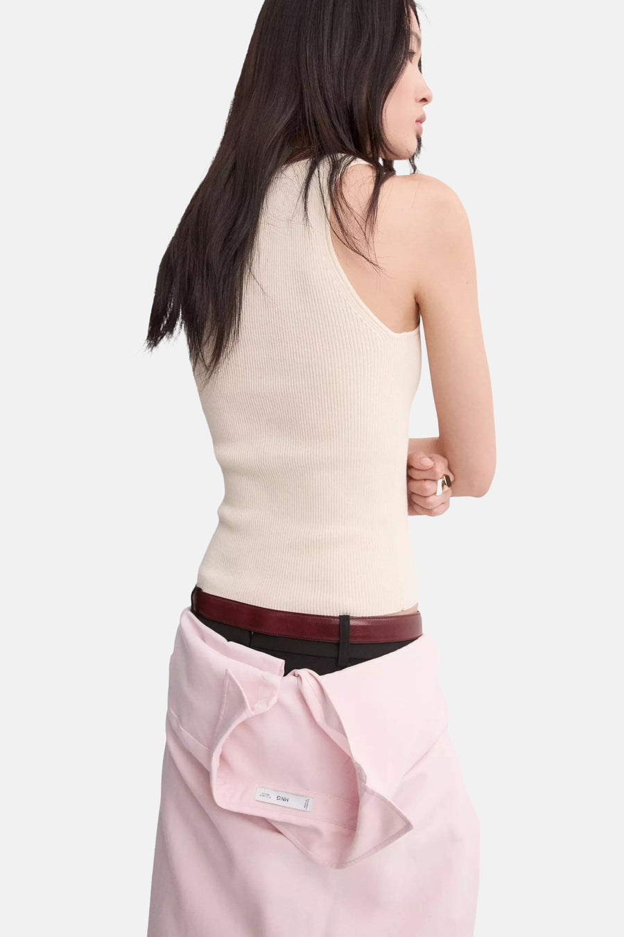 Débardeur côtelé beige de MANGO, porté avec une ceinture foncée et une chemise rose nouée à la taille.