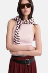 Roze mouwloos top met ribbels van MANGO, van achteren gedragen met een gestreepte roze en bruine trui om de taille geknoopt en een bordeauxrode rok.