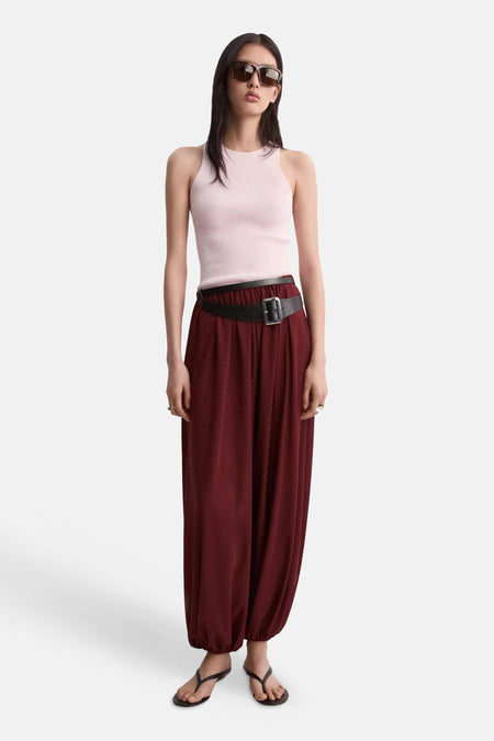 Top rose côtelé sans manches de MANGO, porté avec un pantalon ample bordeaux et une ceinture noire.