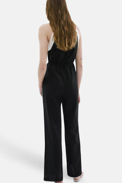 Combinaison noire de MANGO avec des bretelles blanches, taille resserrée et jambes larges, vue de dos.